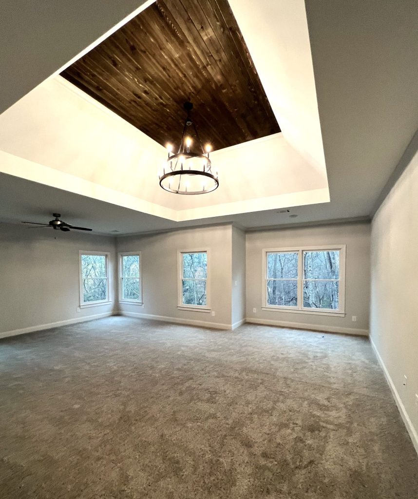 Kingsley Custom Owner's Suite Bedroom with Tray Ceiling and Wooden Paneling and white walls