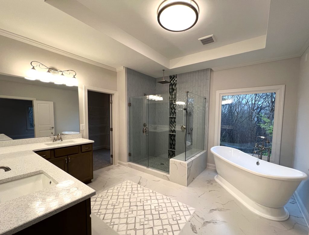 custom owner's bathroom with freestanding tub, large window, dual vanities, and an elegantly tiled glass shower